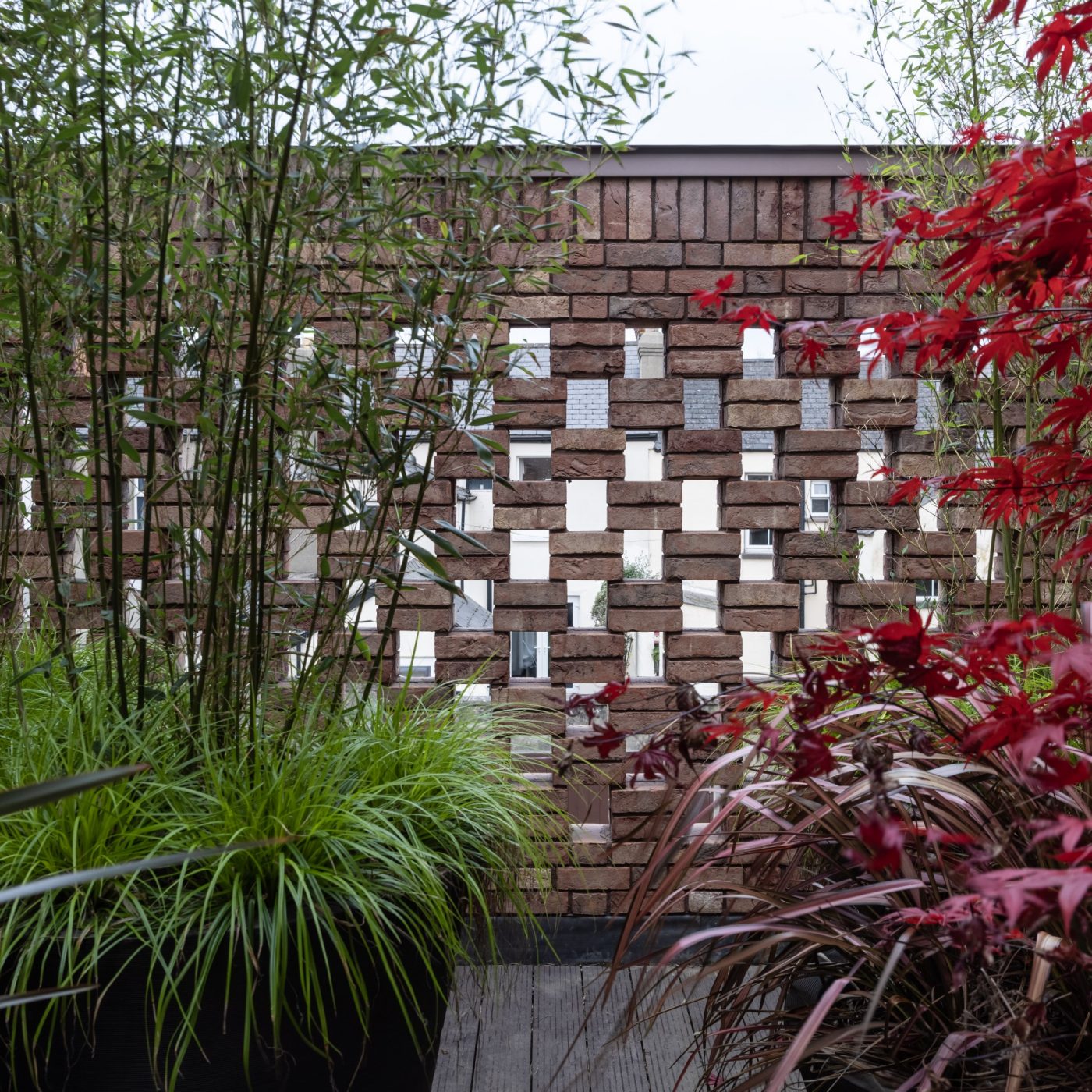 stunning detailed brick wall surrounded with colourful potted tall plants