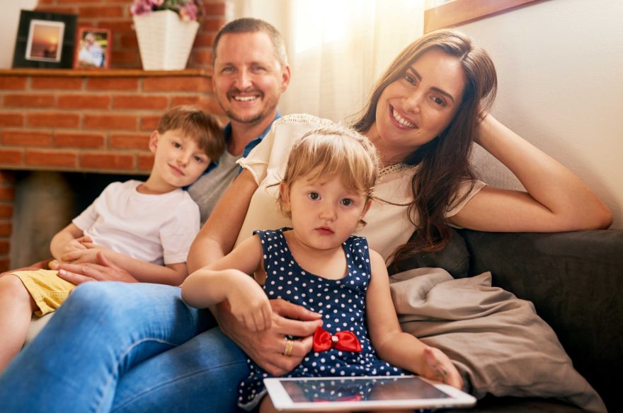 Family of 4 smiling towards the camera in their home