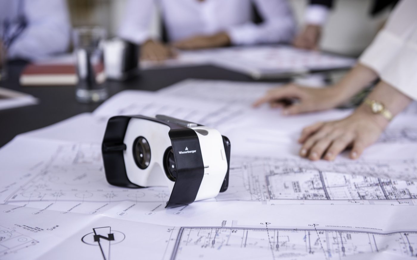 Architectural plans and a VR headset sat on a desk