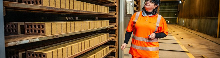Image of a woman in construction clothes walking through a factory