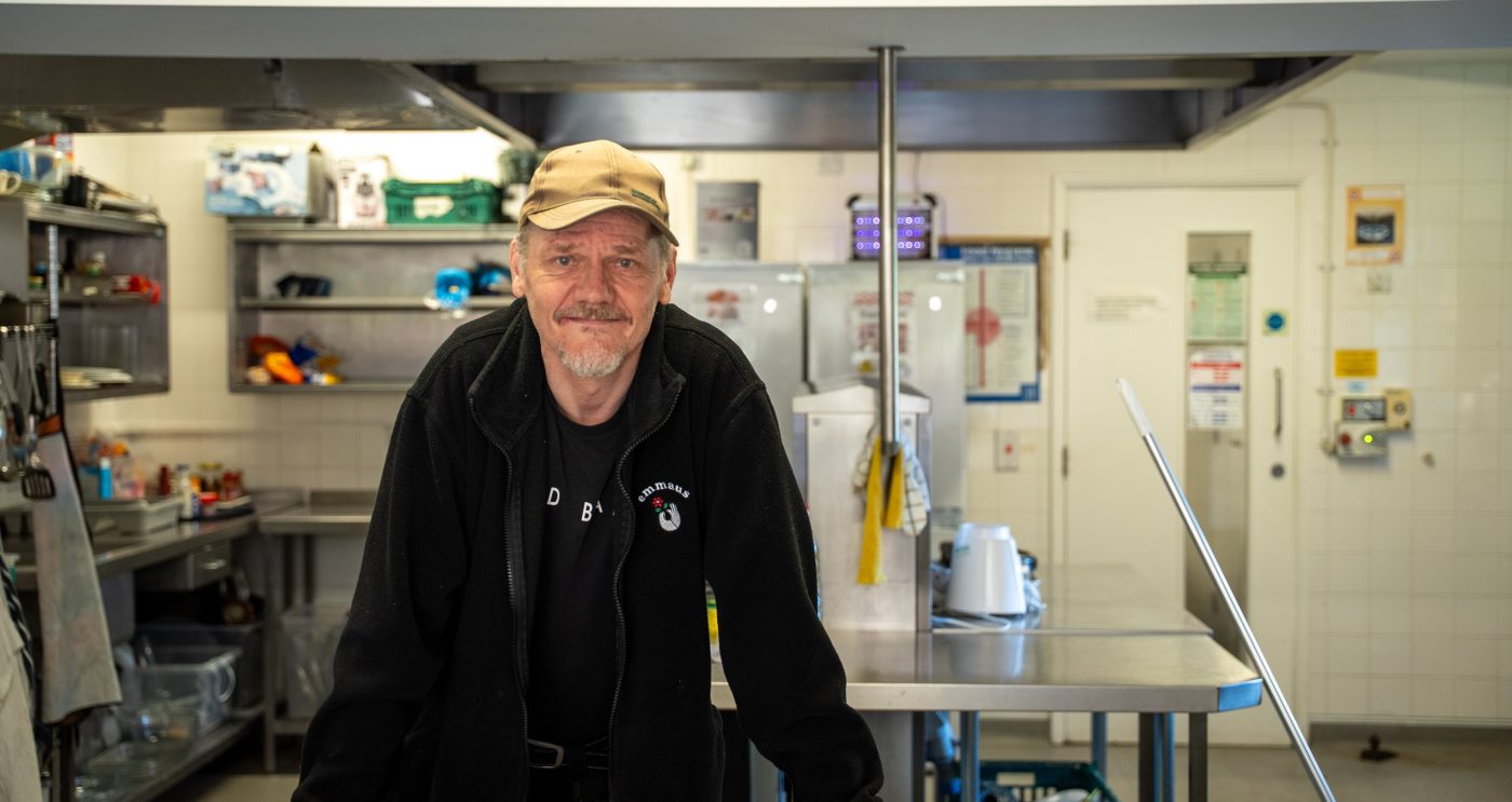 Man stood within a kitchen smiling towards the camera