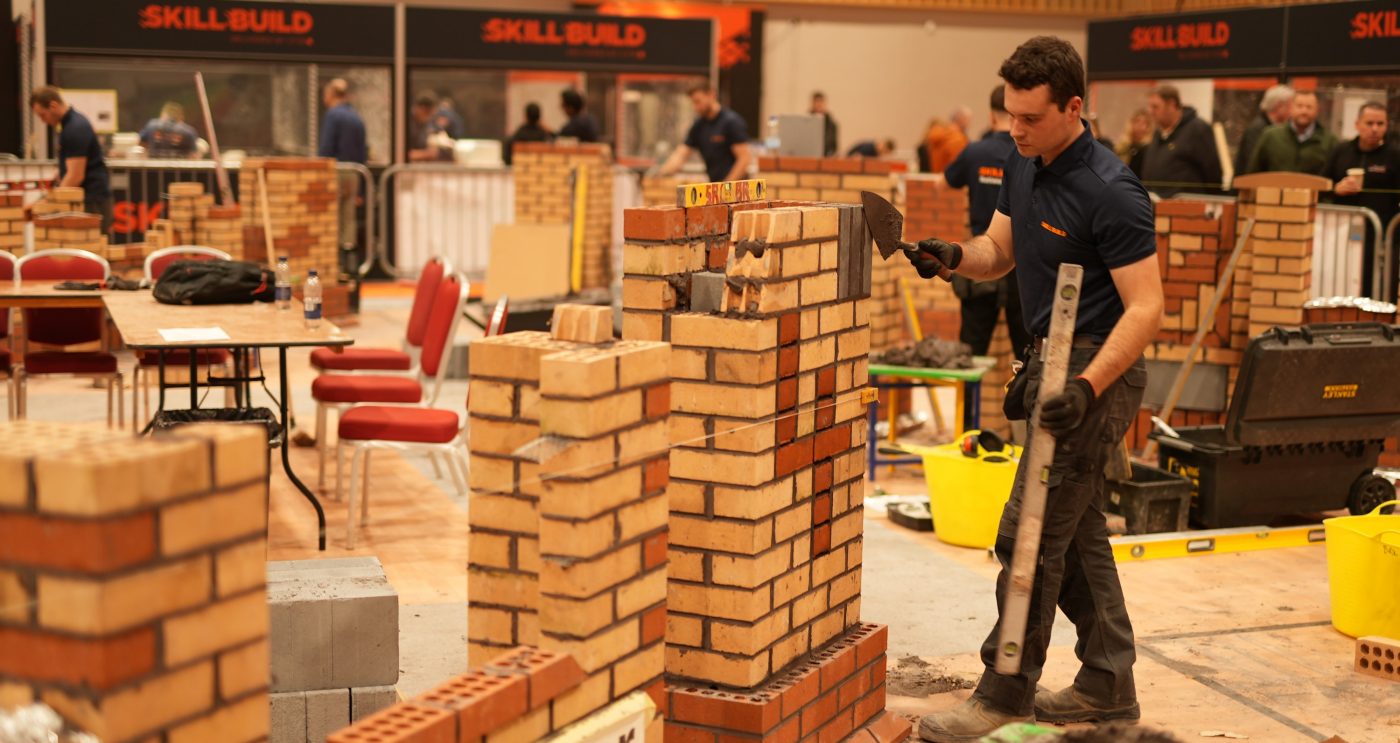 one man building a wall that says '4' using bricks
