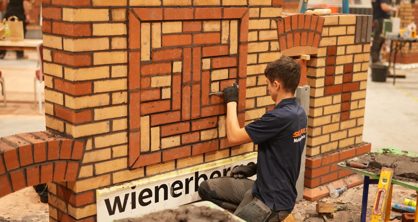 Close up of a trowl being used to build brick wall