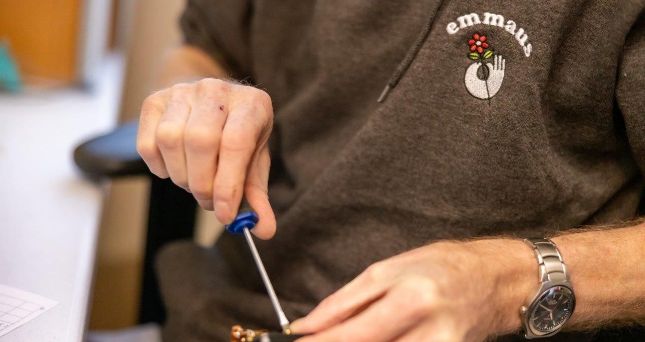 close up of a mans hand using a screwdriver to unscrew an electrical item