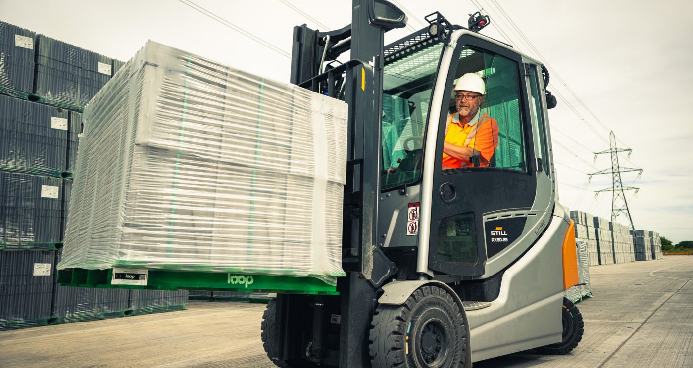 Man in helmet and safety equipment operating a fork lift