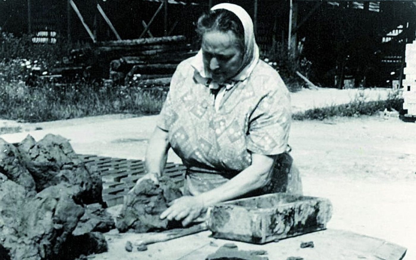 Female brickmaker preparing clay for moulding