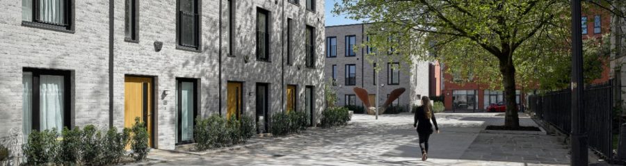 Pedestrian walking past Timekeepers Square grey terraced houses