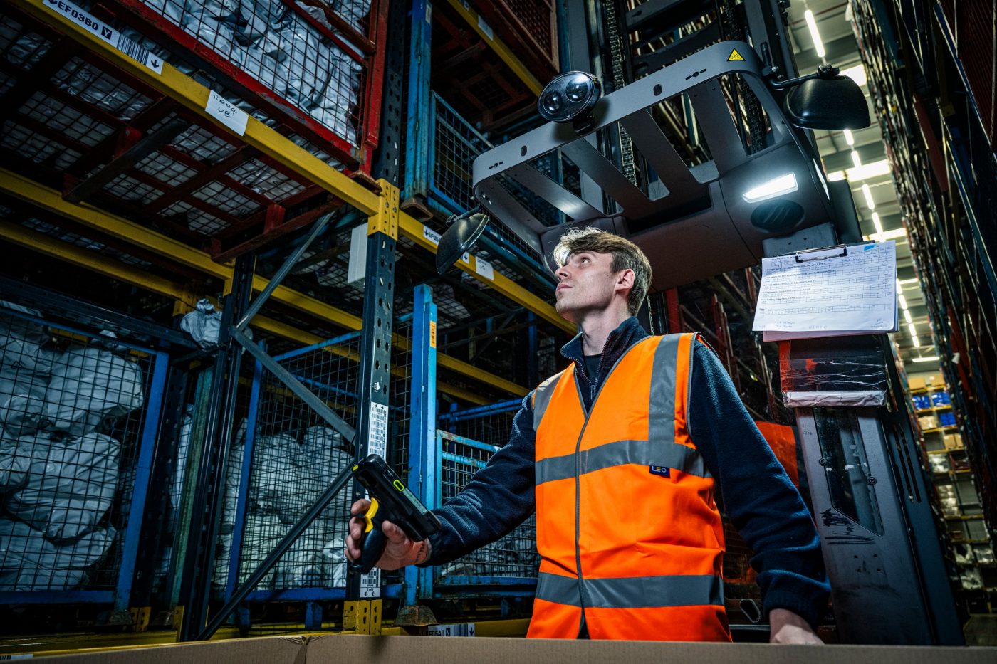 Employee looking up at the tall racks storing products