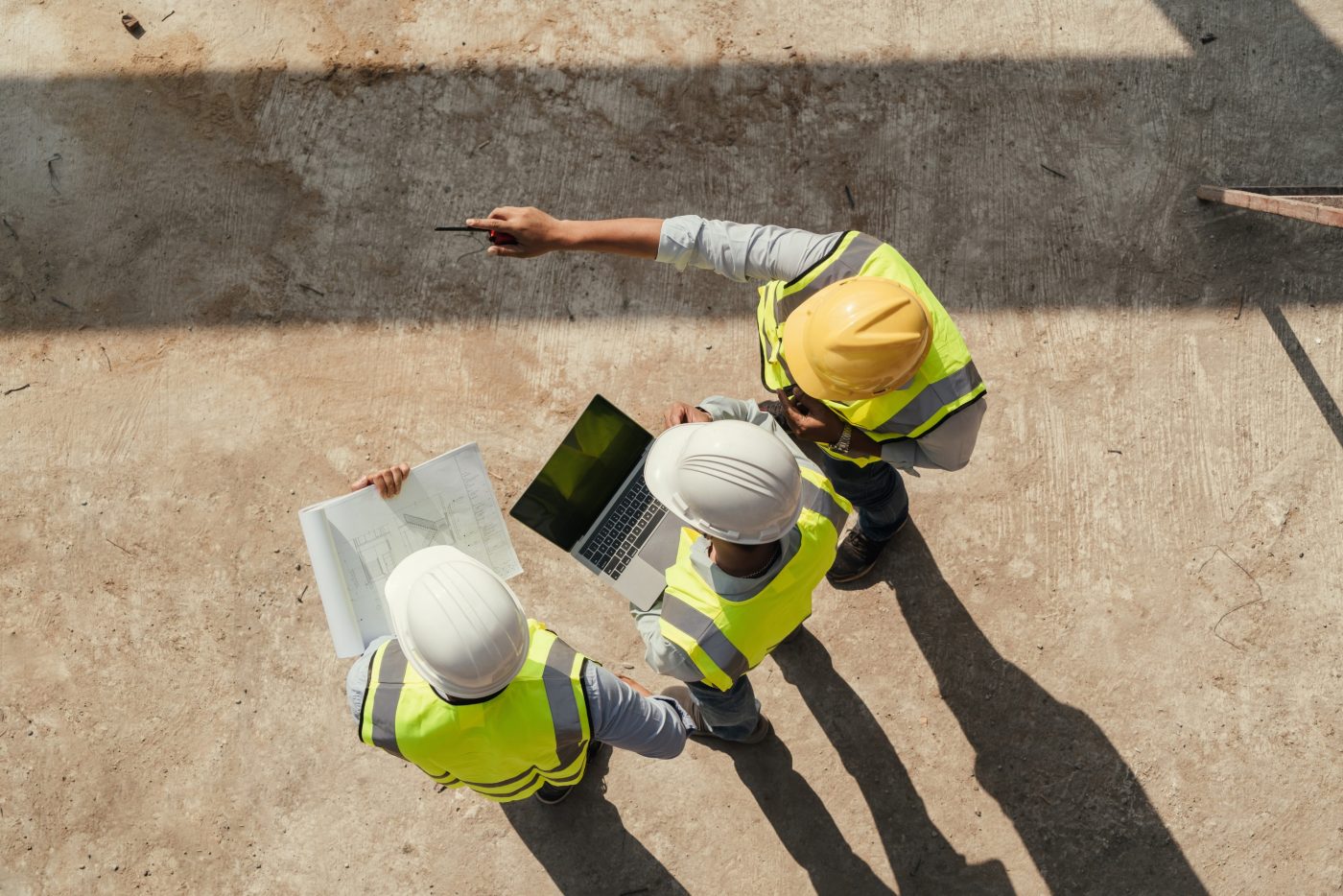 two men on a construction site looking at plans and drawings
