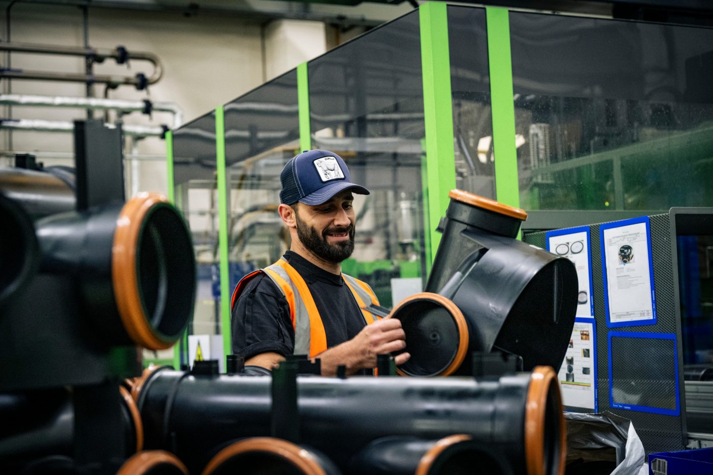 Man holding black plastic pipe from floplast in factory
