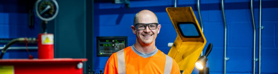 Employee smiling towards the camera a tool room