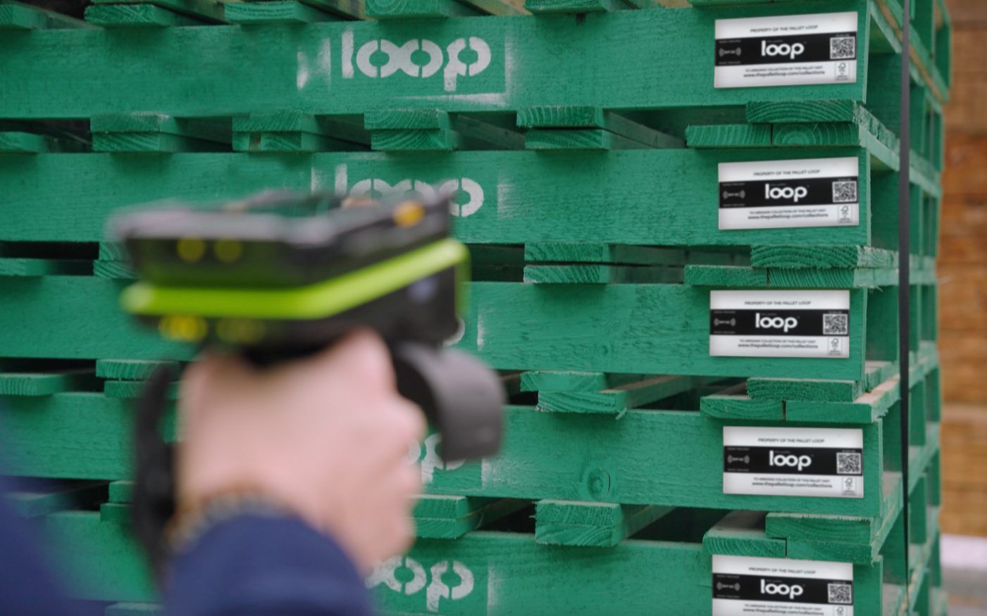 scan gun pointing towards the QR code on a stack of green pallets