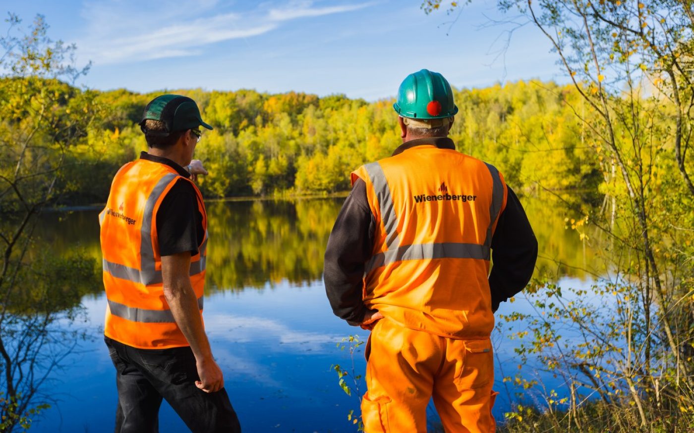 Two men in high vis gear at the edge of a lake