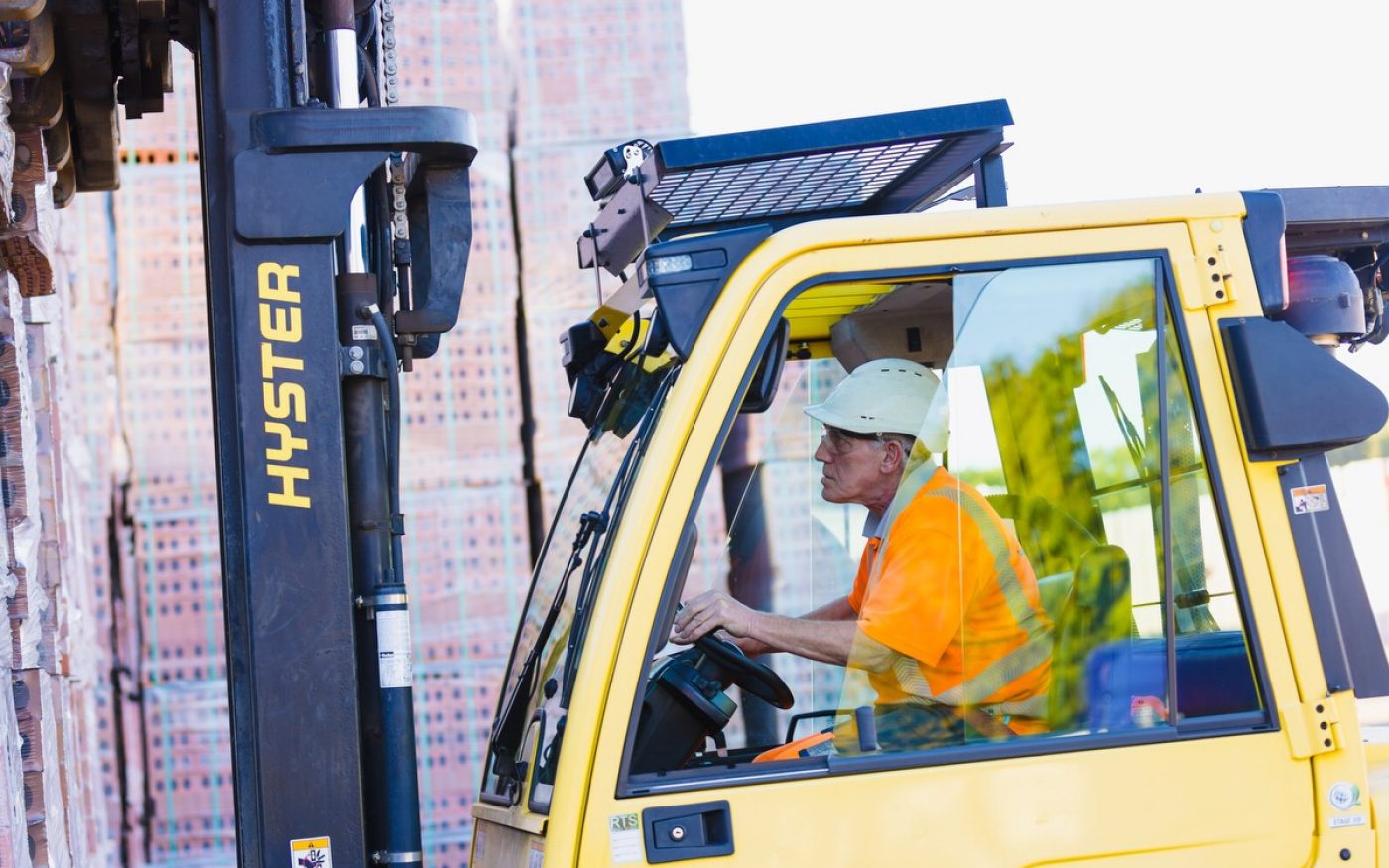 Man in forklift truck moving pallets of brick