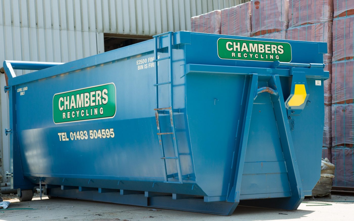 Man watching brick pallets being loaded onto flatbed lorry