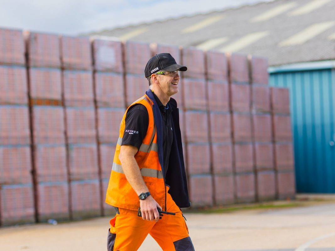 Man wearing hard hat and high viz walking across yard