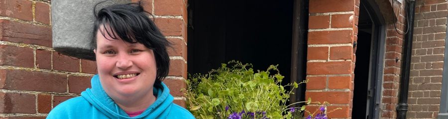 Leighann Curtis from Emmaus stood smiling next to a flower planter
