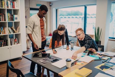 Group of 3 people around a table planning and discussing