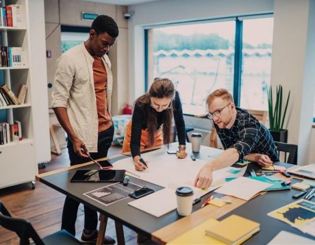 Group of 3 people around a table planning and discussing