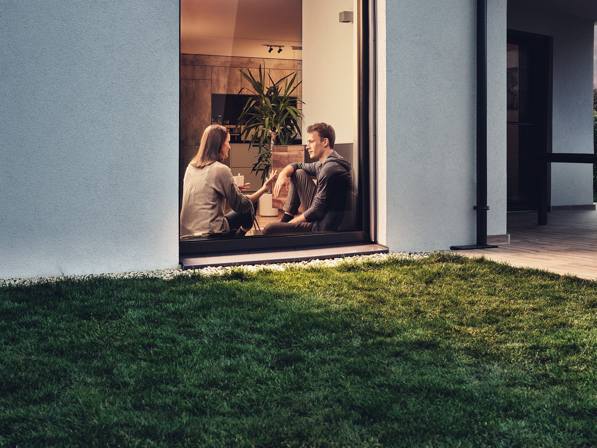Couple sat in window of modern house talking