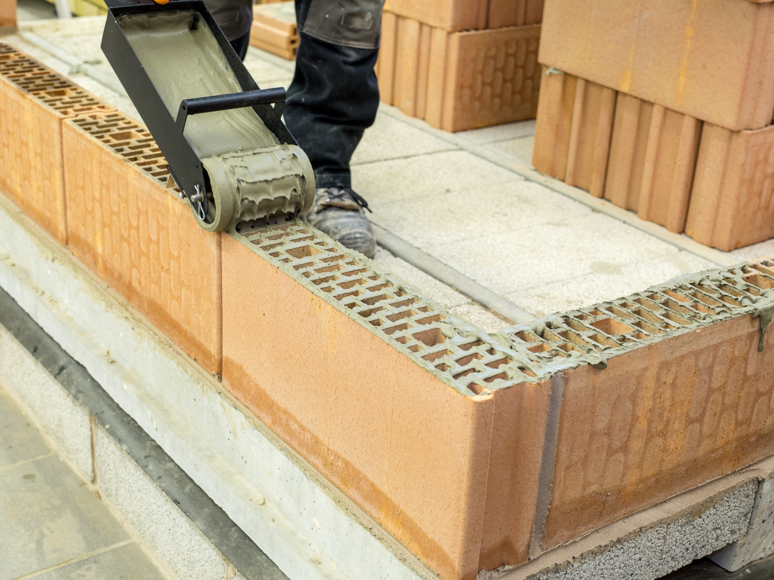 An image of ZeroPlus mortar being applied by a roller onto Porotherm block.