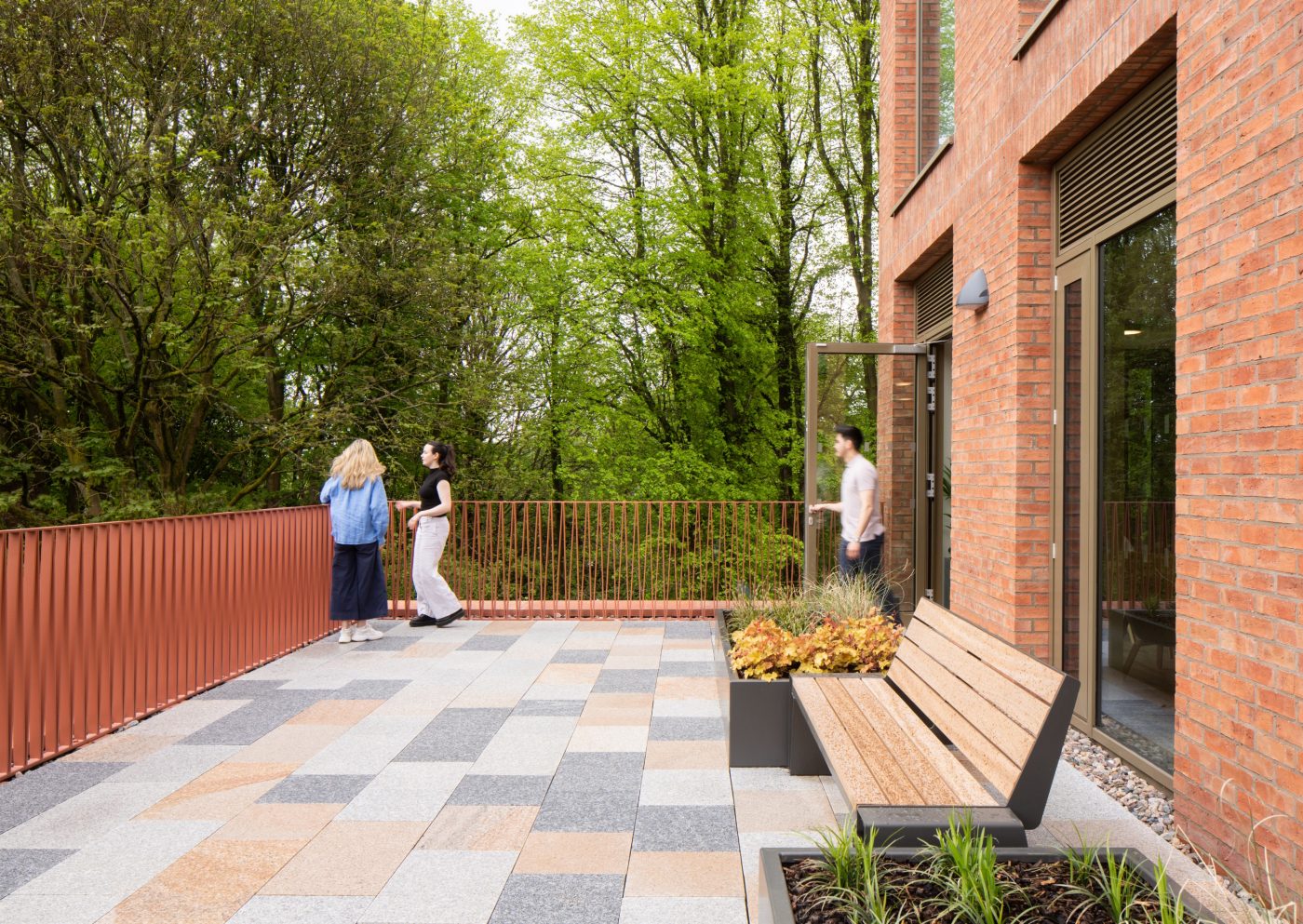 Paved courtyard area looking out over the green woodland area at Queen's University