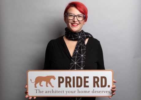 Architect Lisa Raynes holding a Pride Road sign