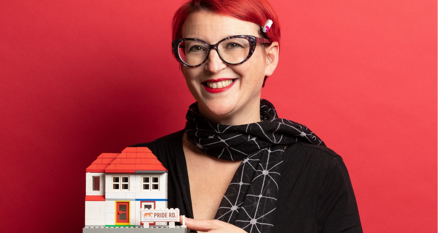 Architect Lisa Raynes with a lego model house and red background