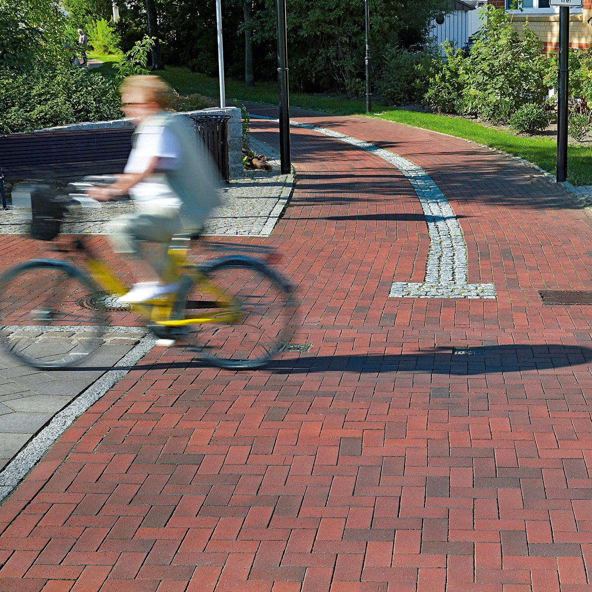 Person riding a yellow bike over a paved public path