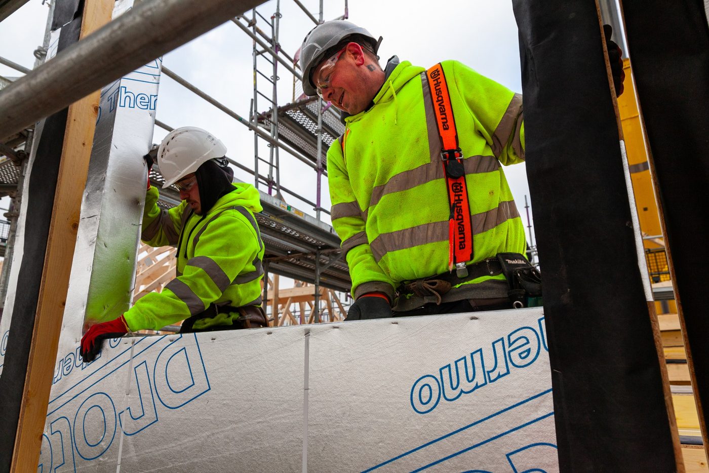 Two builders installing membranes on a building site