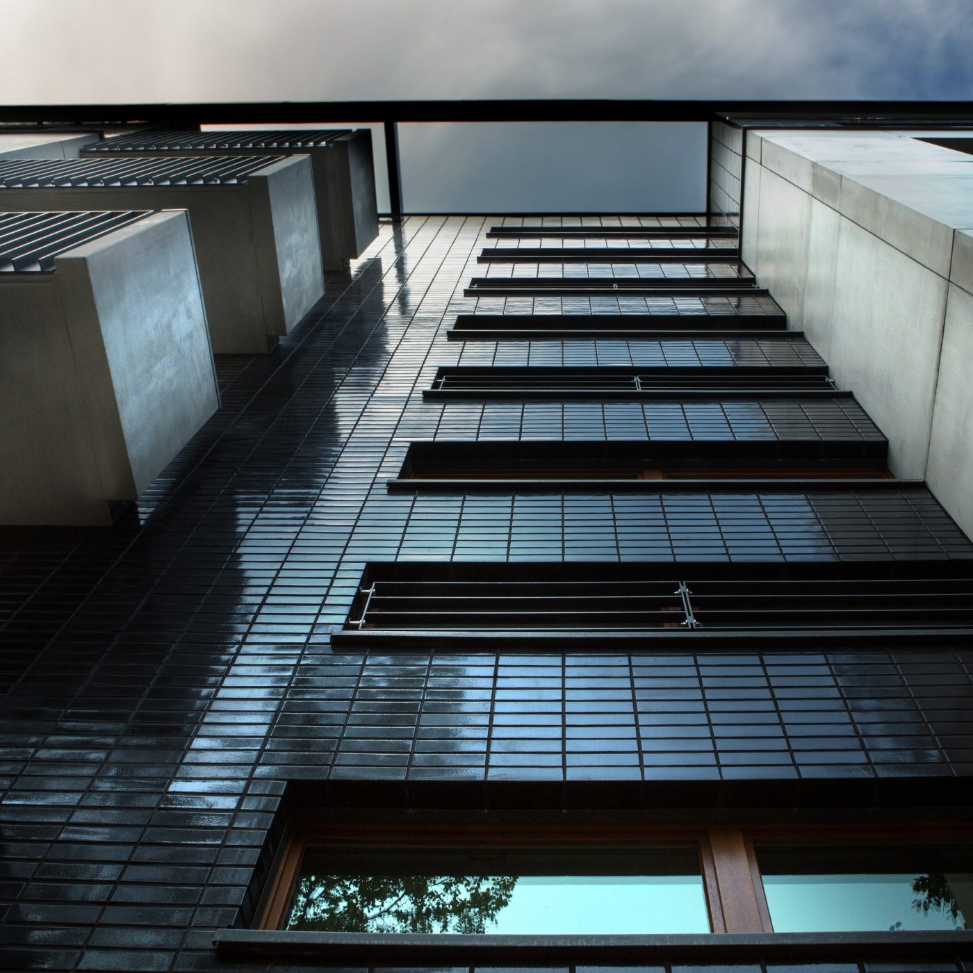 Large red brick detacahed home with blue sky and front lawn
