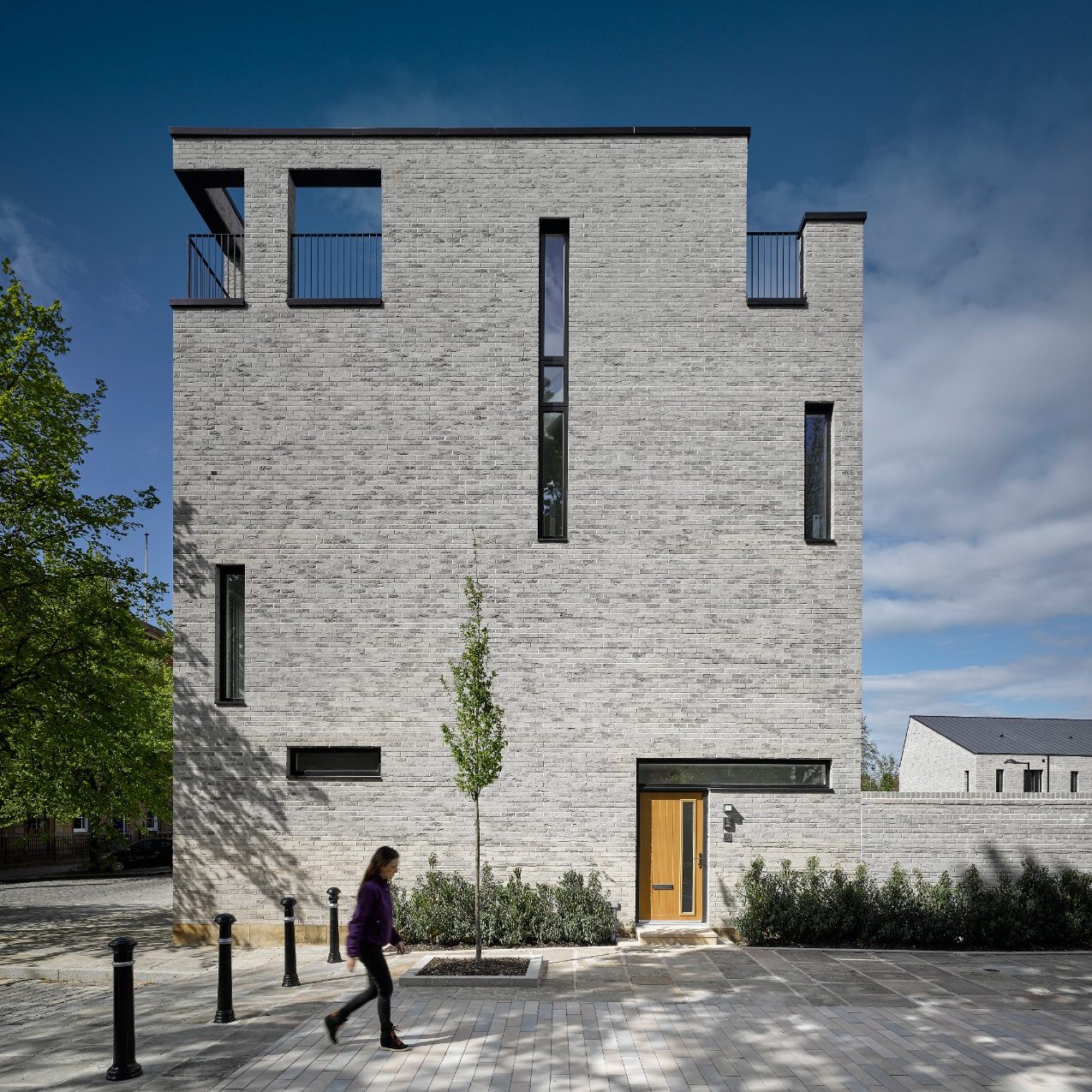Person walking past grey brick building