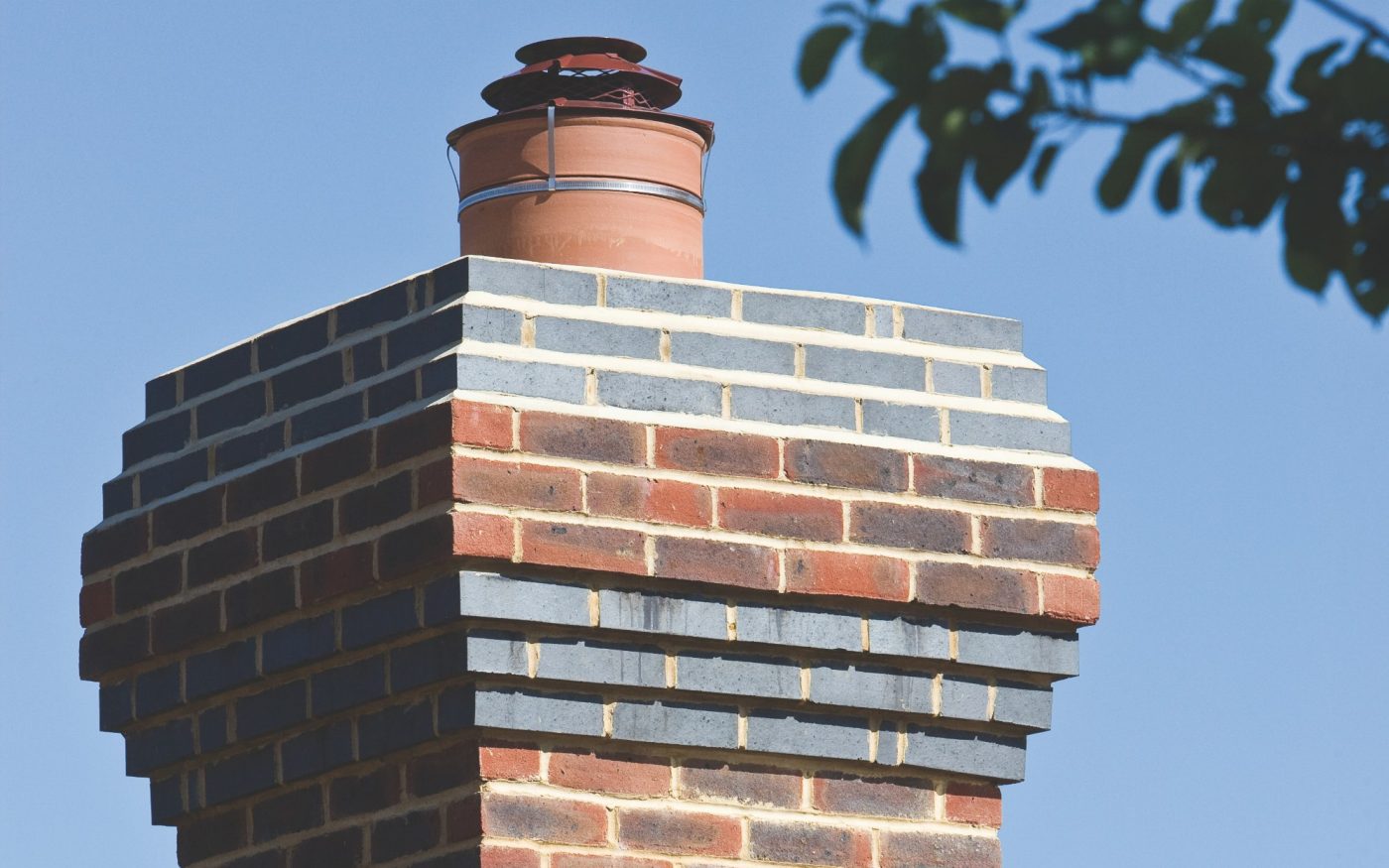 Corbel detailing on brick chimney against blue sky