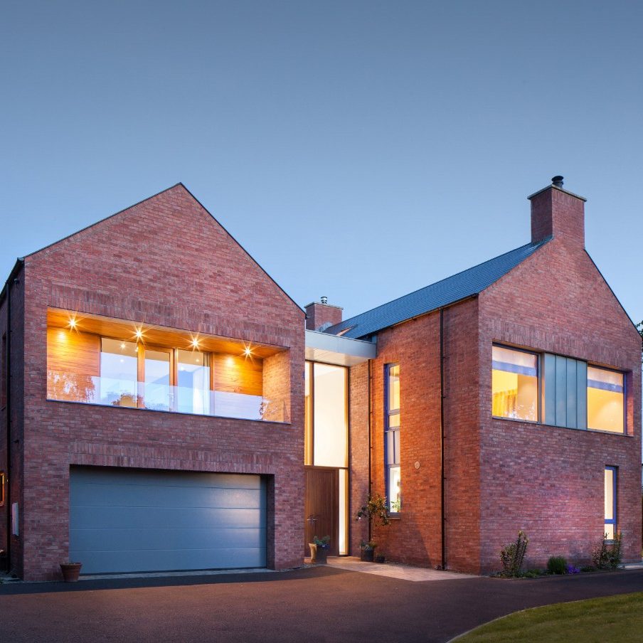 Modern brick house at dusk with lighted windows