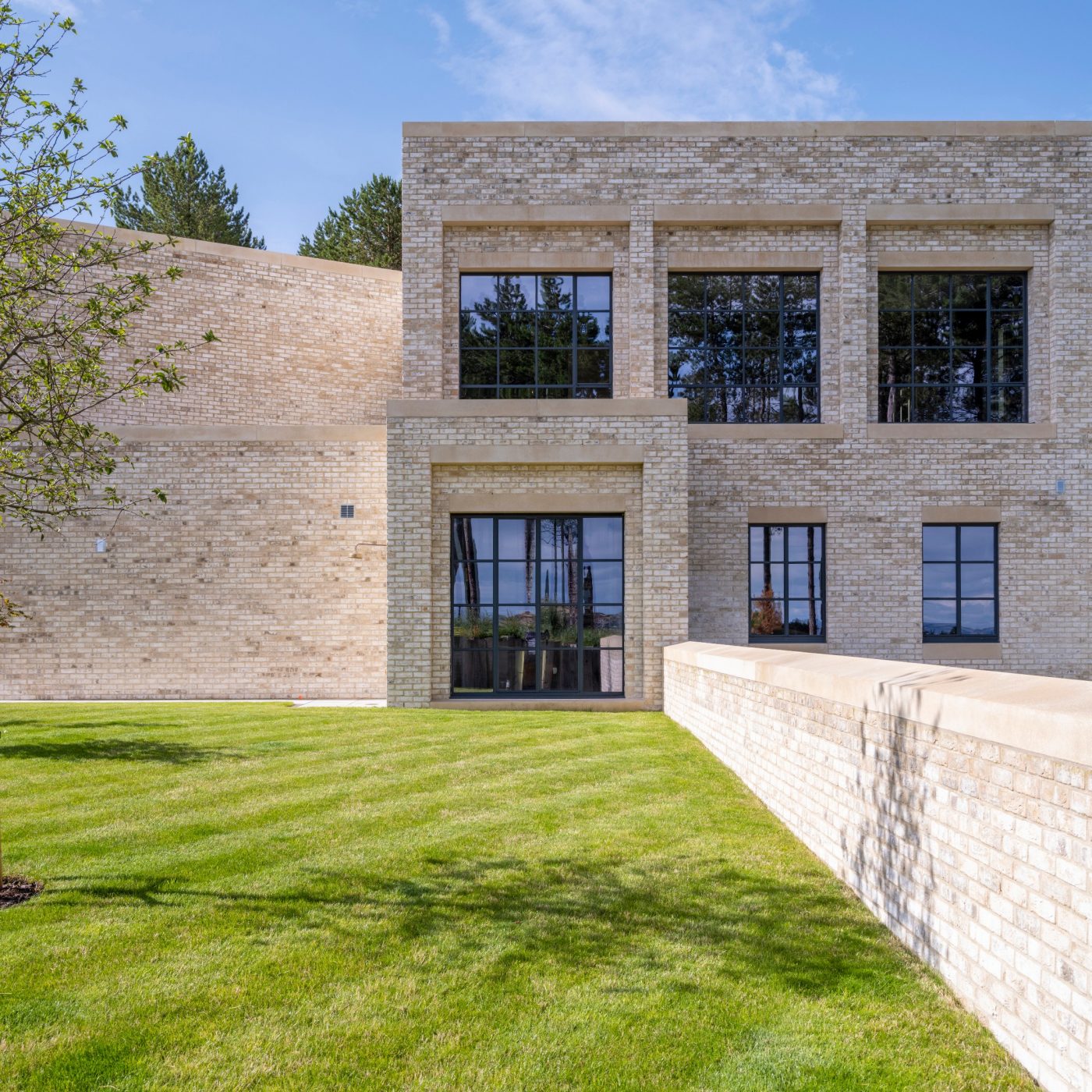 Large cream brick residential property with blue sky and front lawn