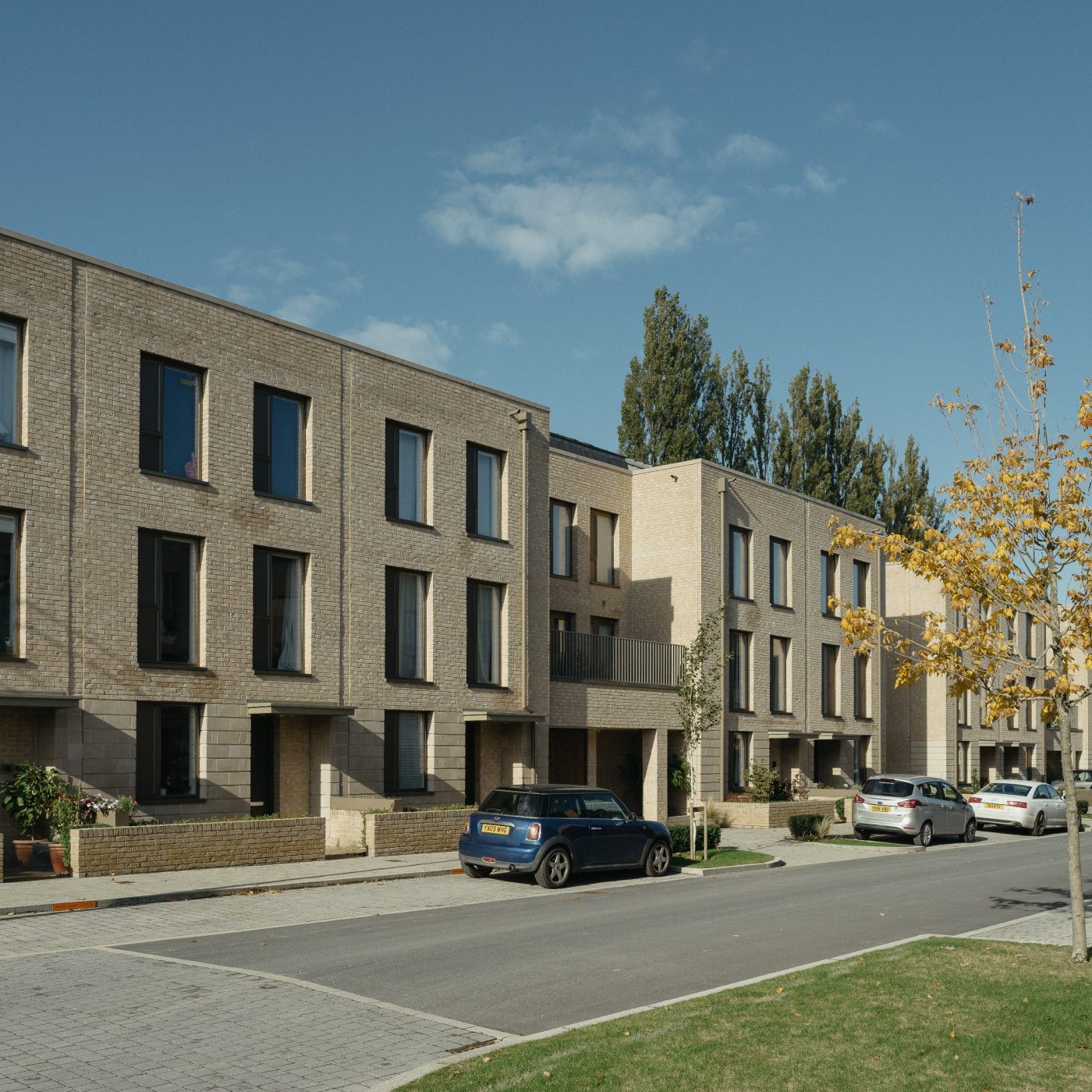 Modern brick terraced houses at dusk with cars parked outside