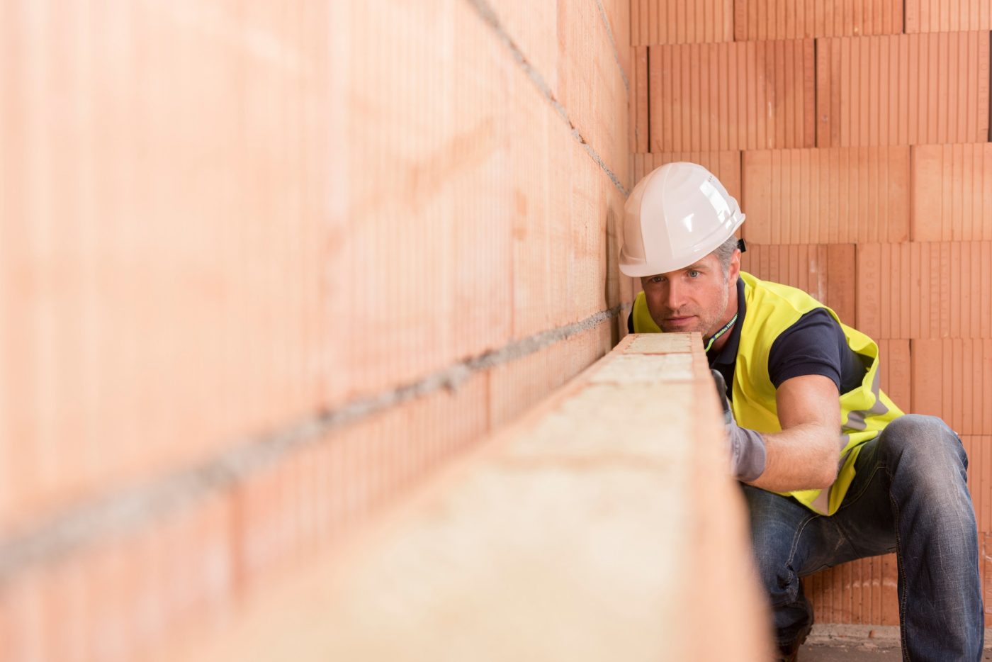 Man wearing hard hat looking at Porotherm clay block wall