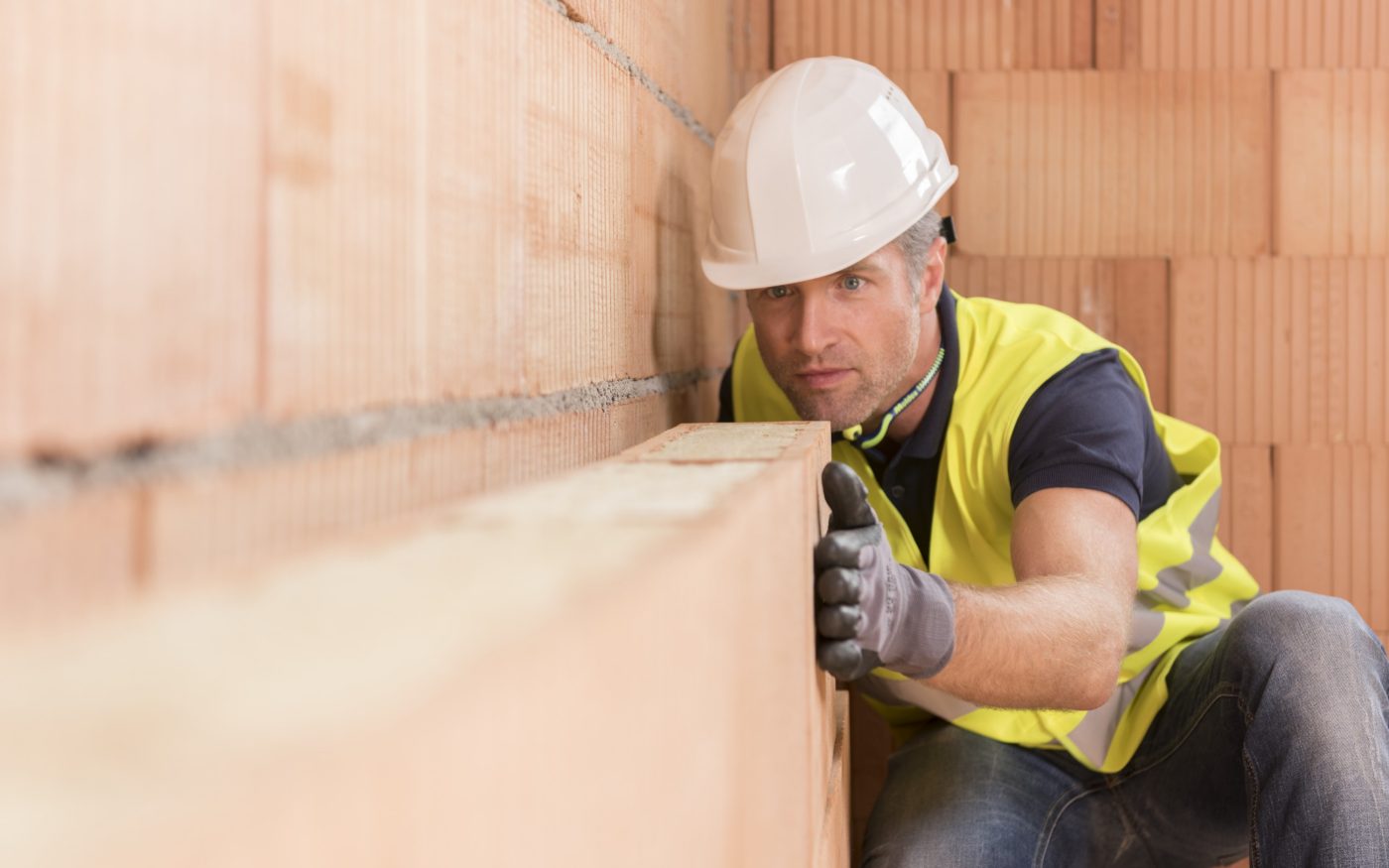 Man in safety gear inspecting Porotherm clay block wall