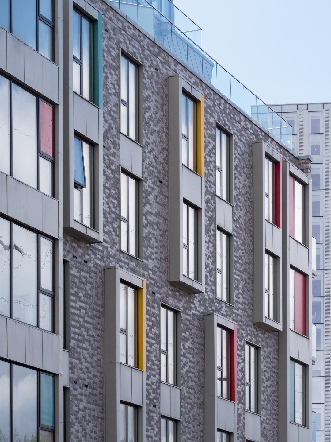 Man walking along balcony against colourful facade of apartment building