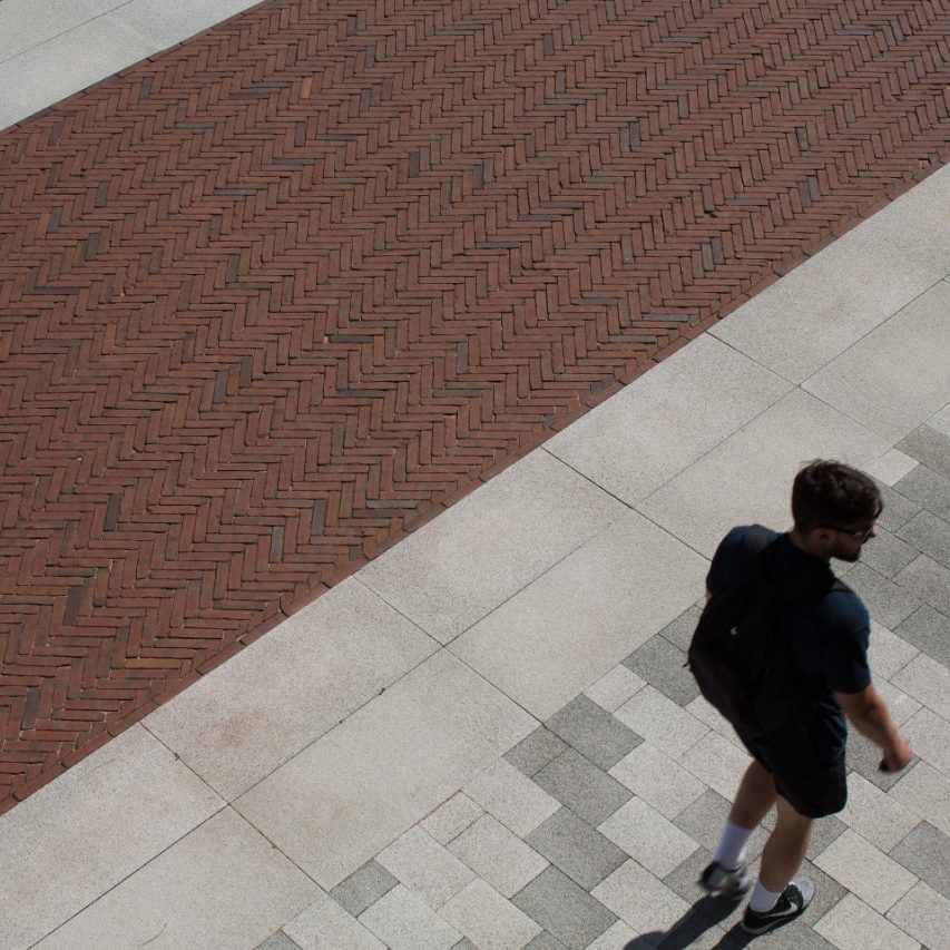 Man walking across paved university quad