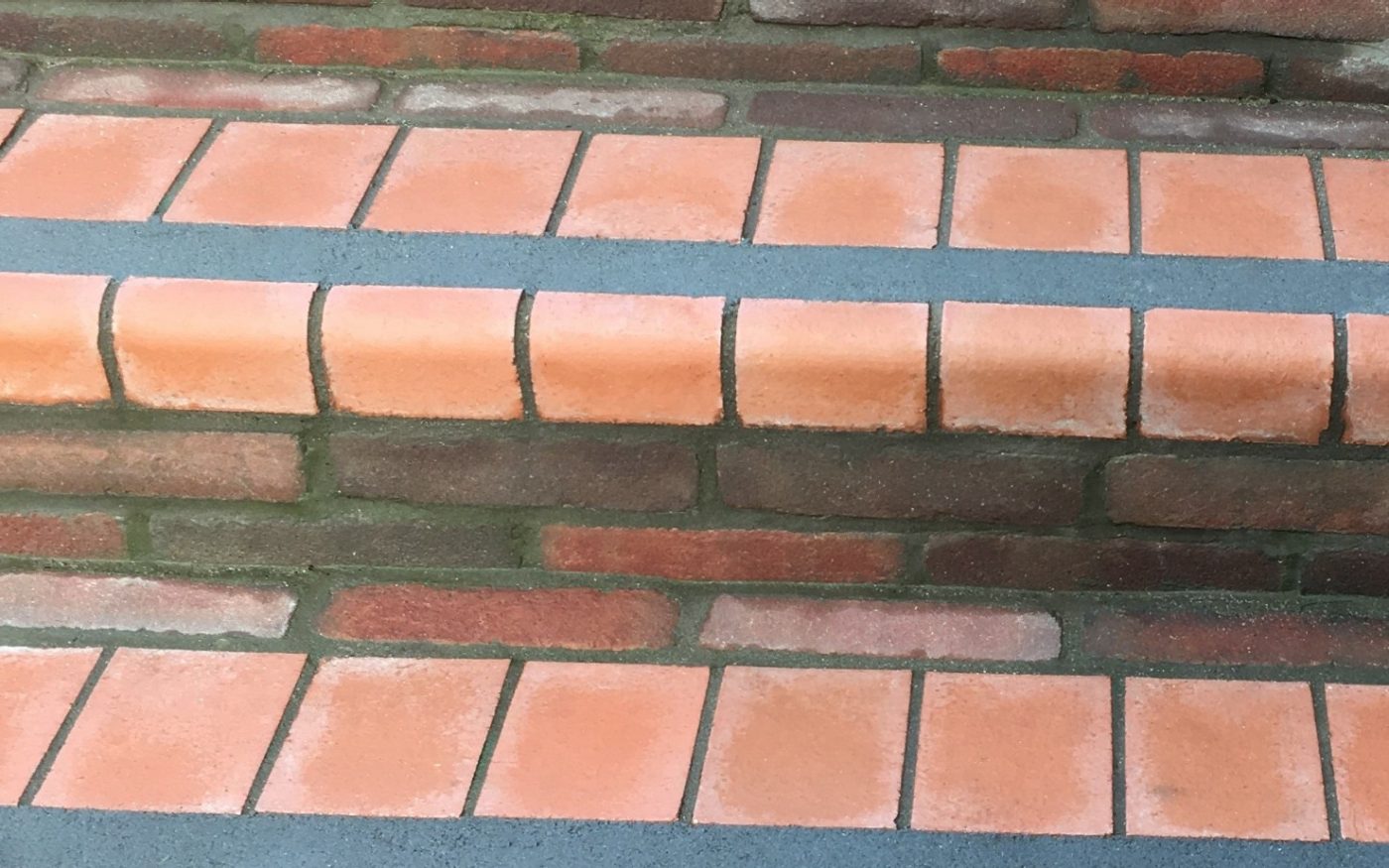 Grey stripe across red clay paver steps to support visually impaired people