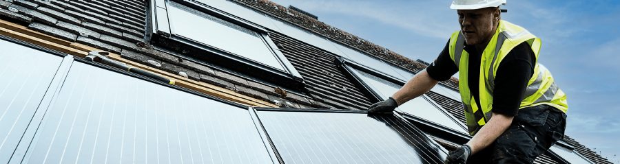 Man in safety wear on roof installing in-roof solar panels