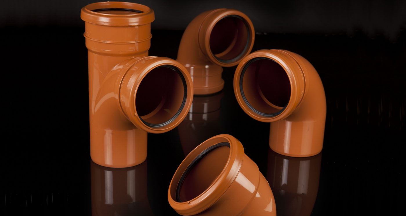 Long brown plastic pipes stacked within storage unit