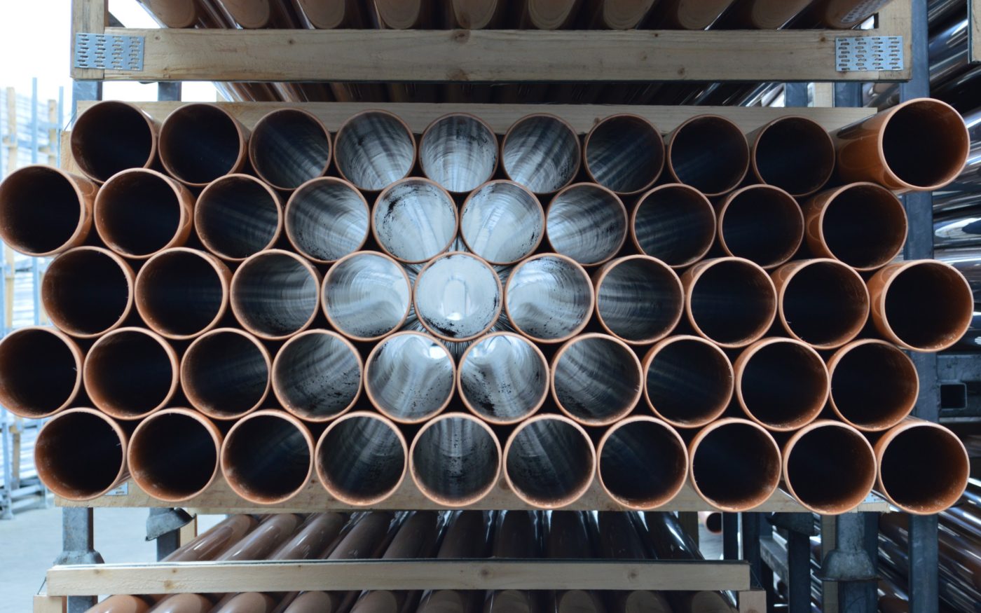 Stack of brown plastic pipes stored on industrial shelving.