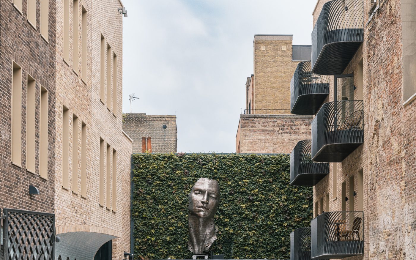 Public courtyard with a metallic sculpture in the centre and tall buildings either side