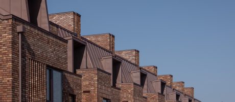 Row of red brick modern terraced houses with blue sky