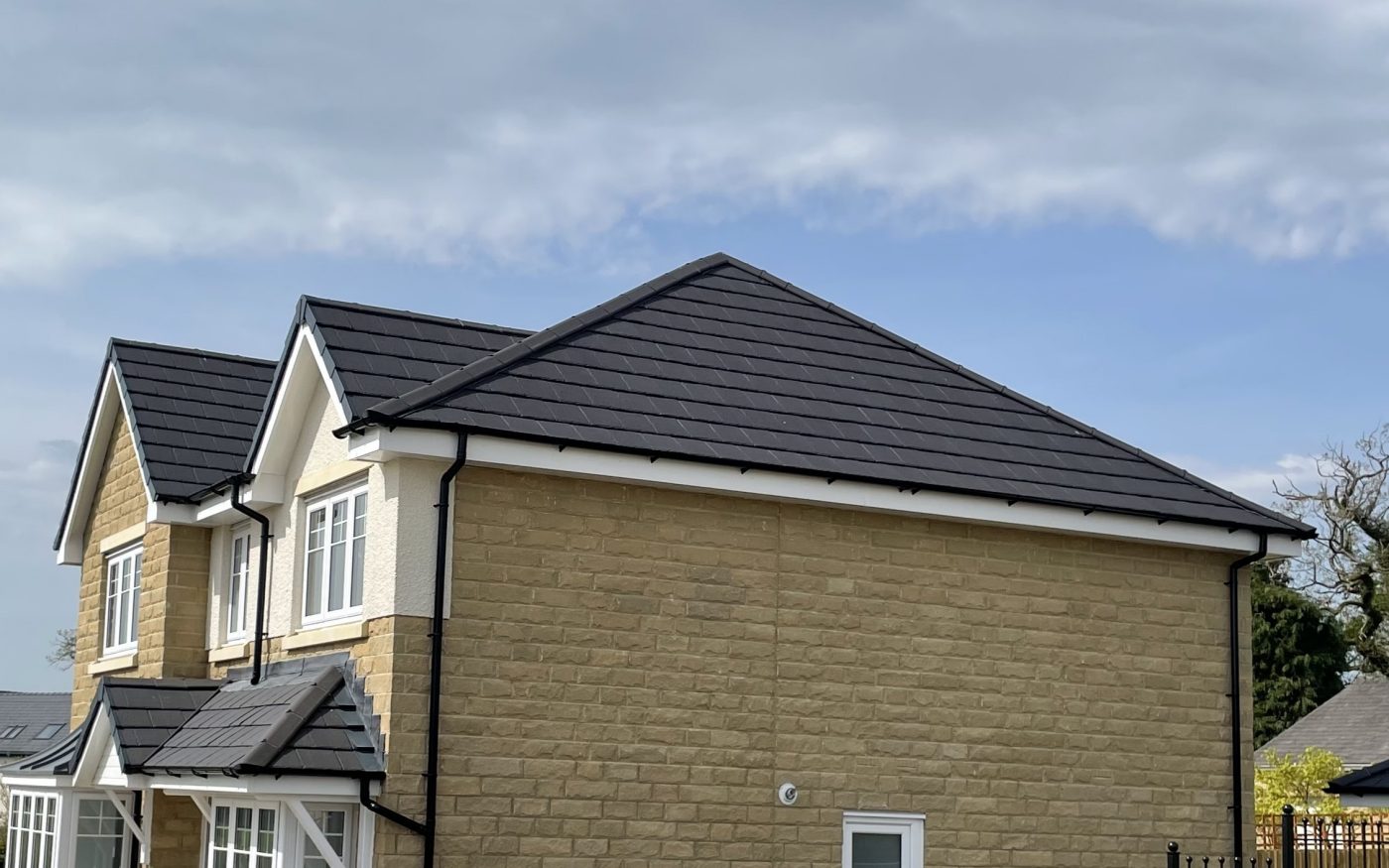 Dark grey roof tiles against blue sky and clouds