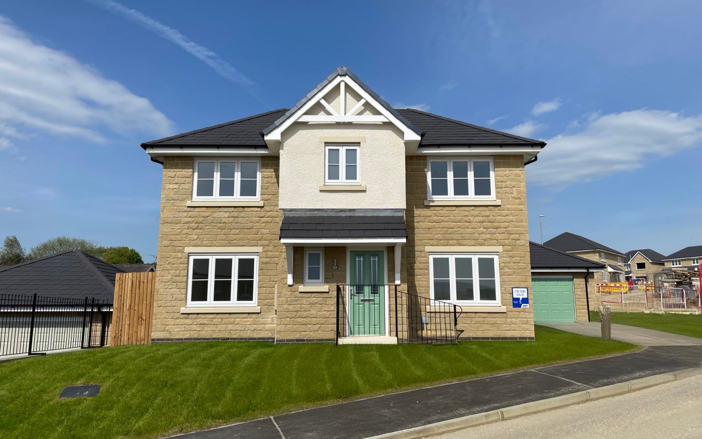 Beautiful buff house with green front door and freshly cut front lawn