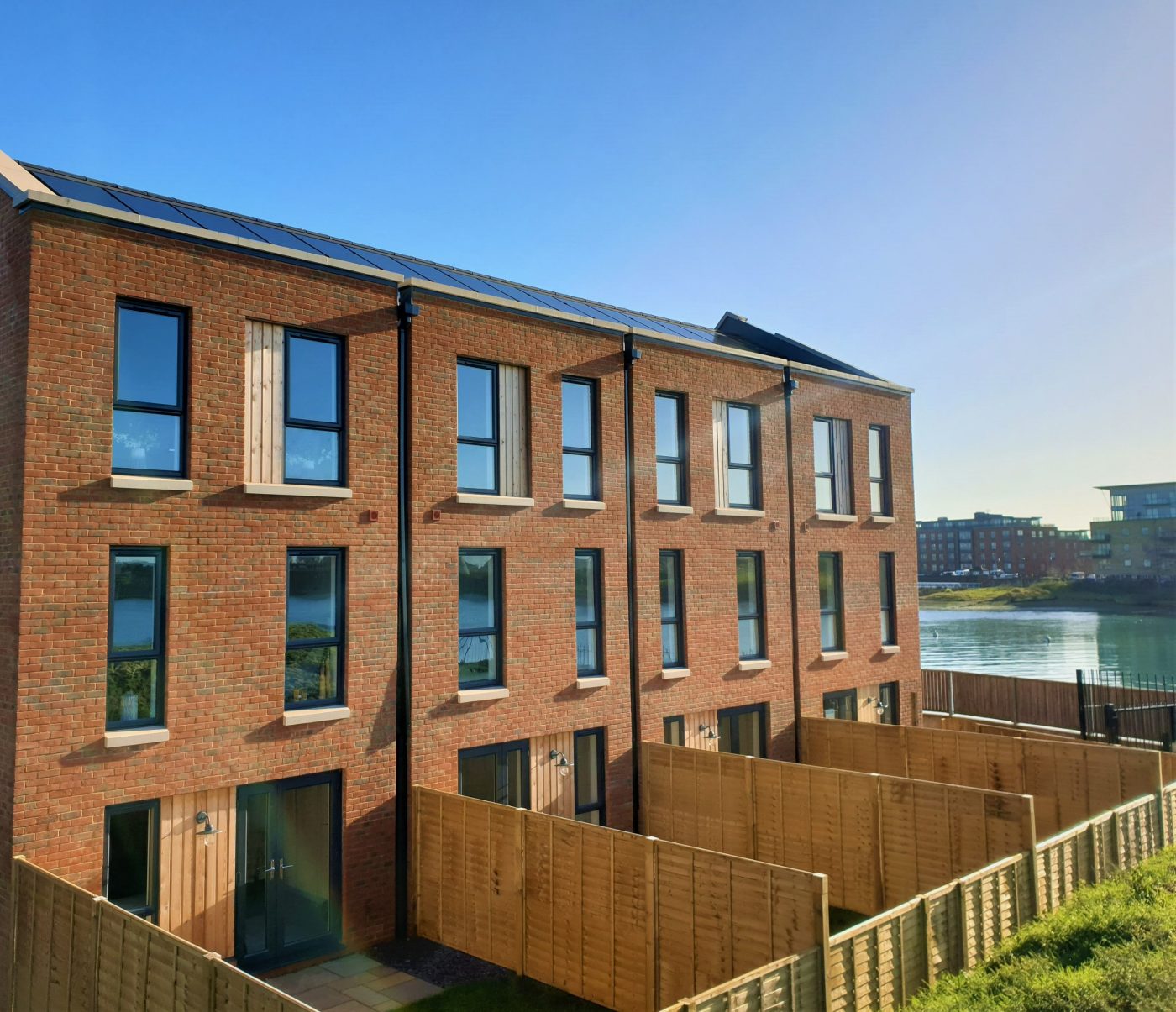 Modern terraced houses with fenced yards and river in background