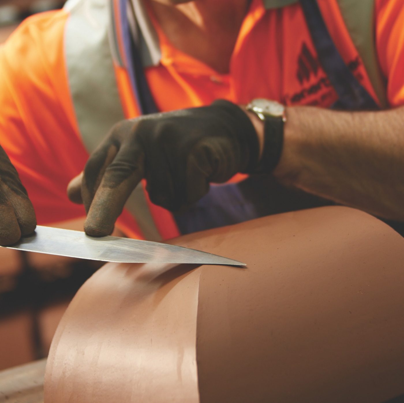 Man wearing gloves carving special shaped brick